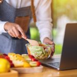 A woman videoblogger cooking in the kitchen and filming, online learning cooking class concept