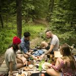 High Angle View Of Friends Eating Food While Sitting Porch In Forest